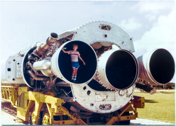 Kai MacLaren stands in the booster-engine nozzle of an Atlas ICBM, at the Air Force Space and Missile Museum at Cape Canaveral Air Force Station, Florida. This is not a mockup or replica, but instead is actual flight hardware, taken out of service, unflown. Behind Kai, the cover to the engine compartment has been removed, exposing the components within. Photo by James MacLaren.